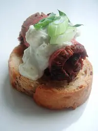 A piece of bread with meat and whipped cream on it.