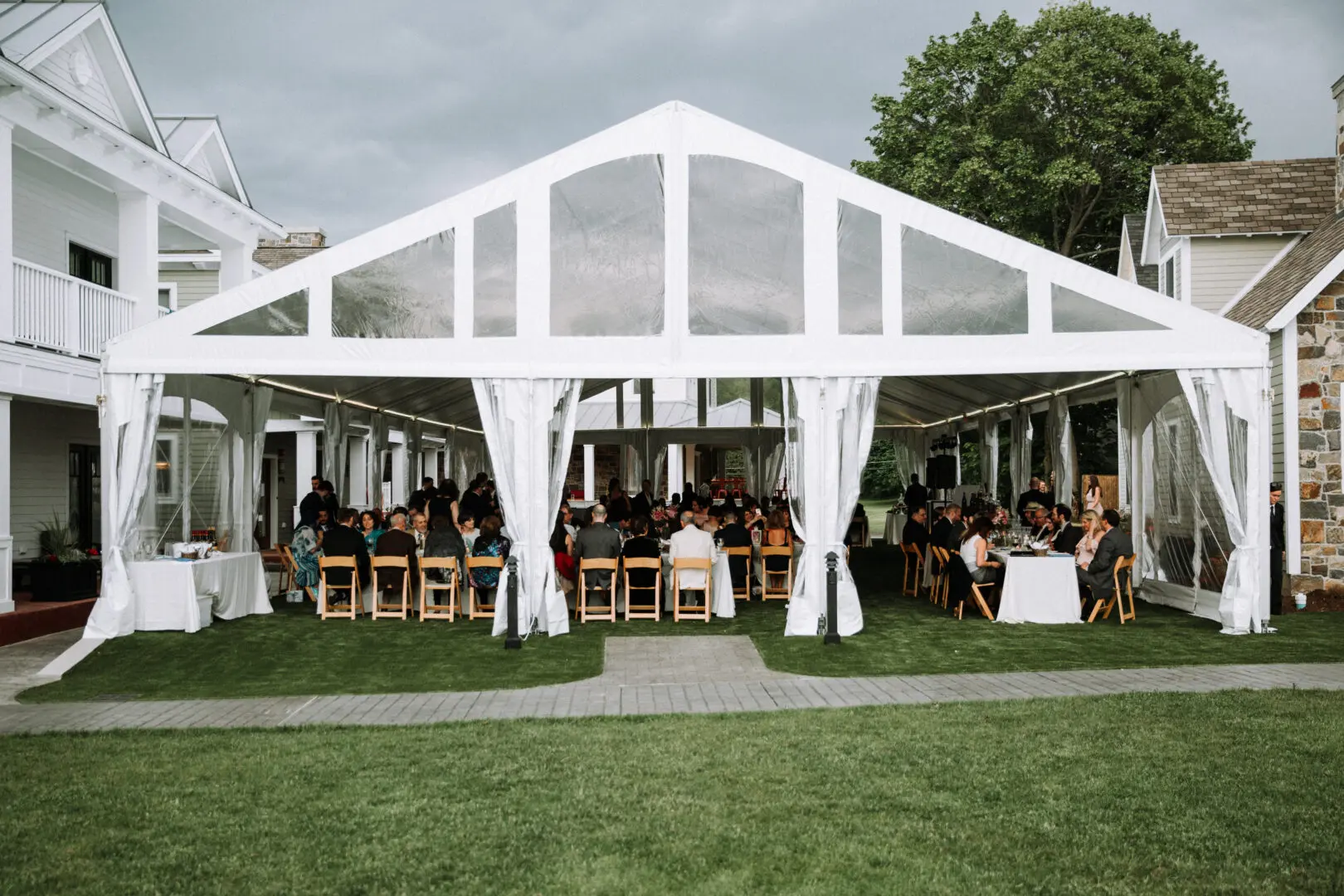 A large white tent with people sitting at tables.